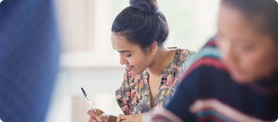 Students sat in a classroom looking down and writing during a lesson