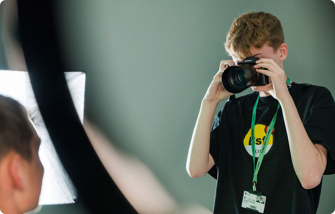 Student holding camera taking picture in the studio