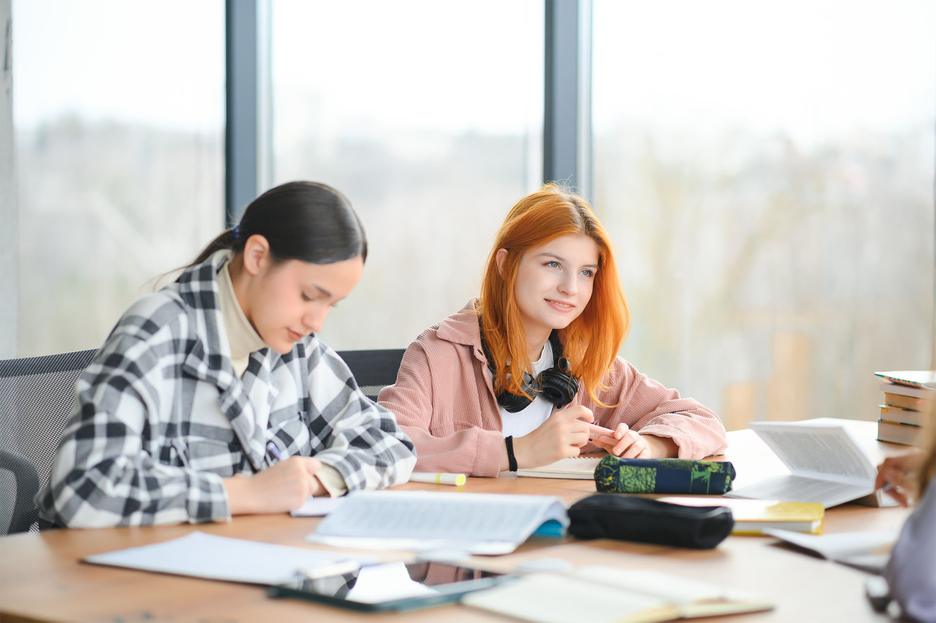 Two female students sitting in classroom with notes on table