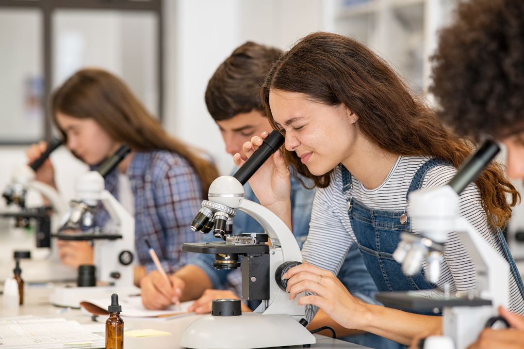 Science students looking through microscopes in the science lab