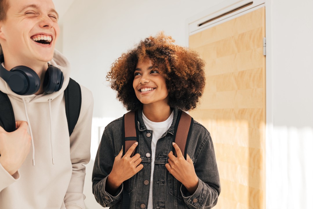 Two students walking down the college hallways laughing and talking with each other