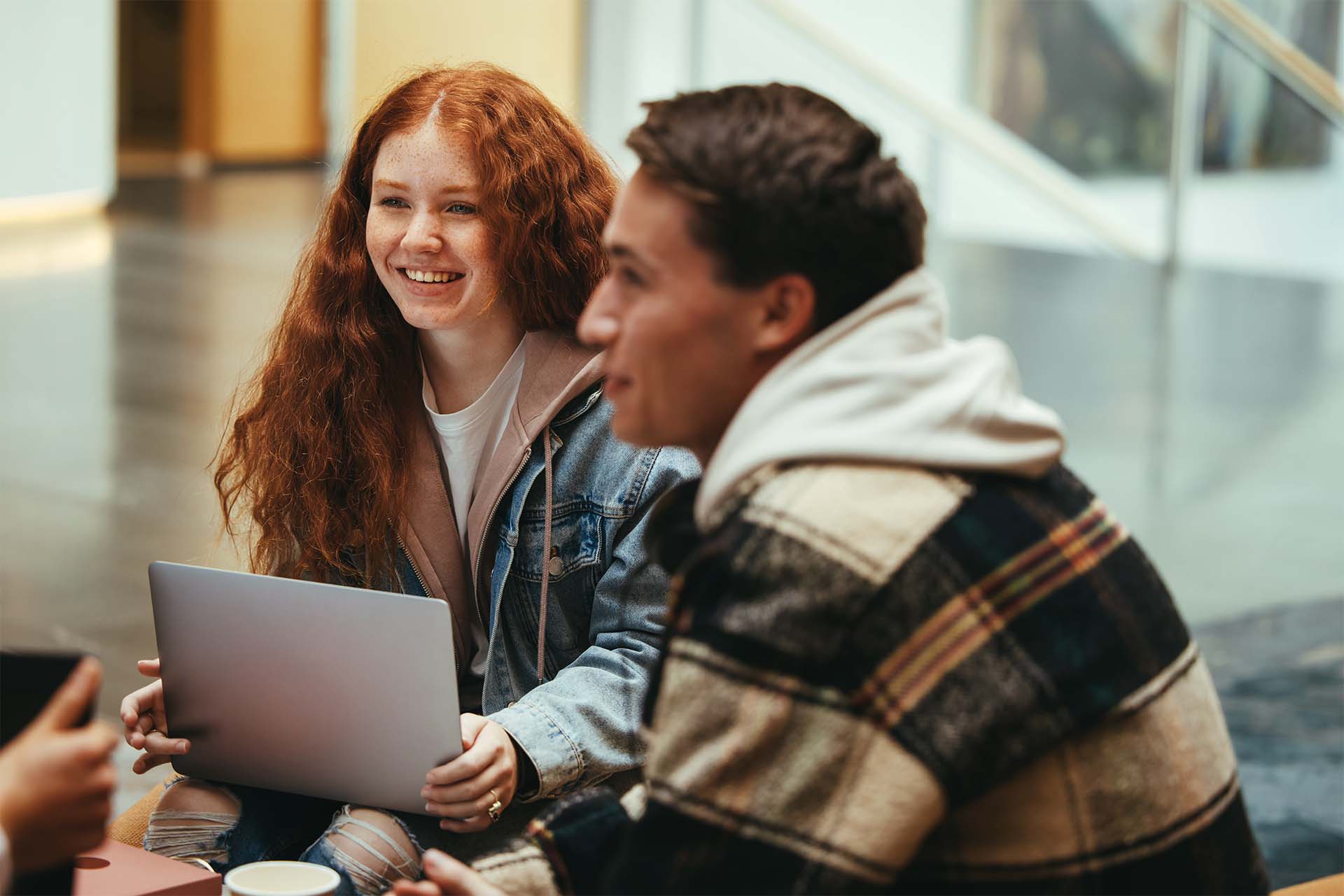 Students smiling sitting down with laptop