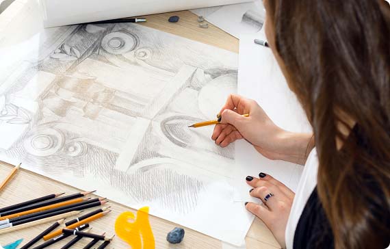 Student sat at desk sketching and shading the archway on an ornate building
