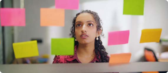 Student looking at colourful post-it notes stuck on a window