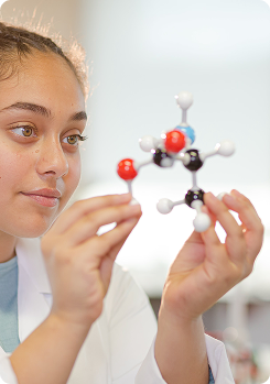 Student wearing lab coat holding molecular models