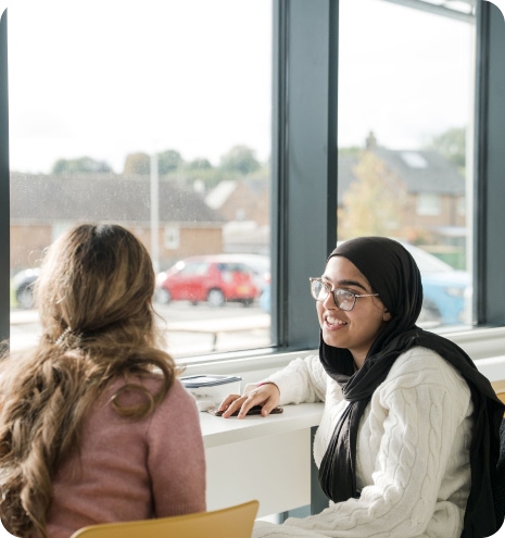Two students sitting down by the window having conversation