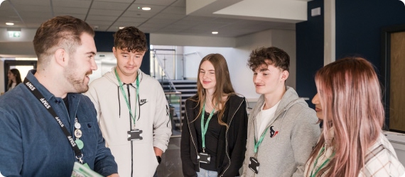 Member of staff and students standing at reception having conversation