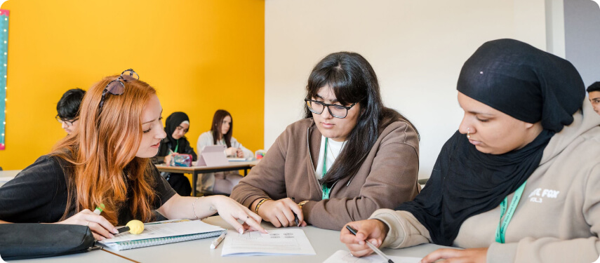 Students sitting in groups in the classroom looking at notes having discussion