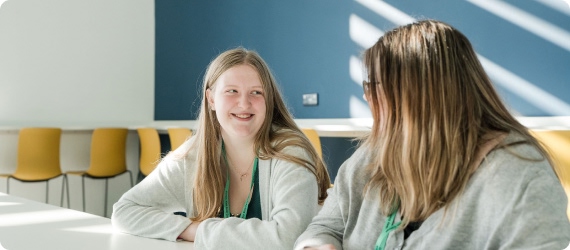 Two students sitting down in the canteen having conversation