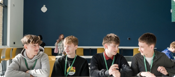Students sat in row having conversation in canteen