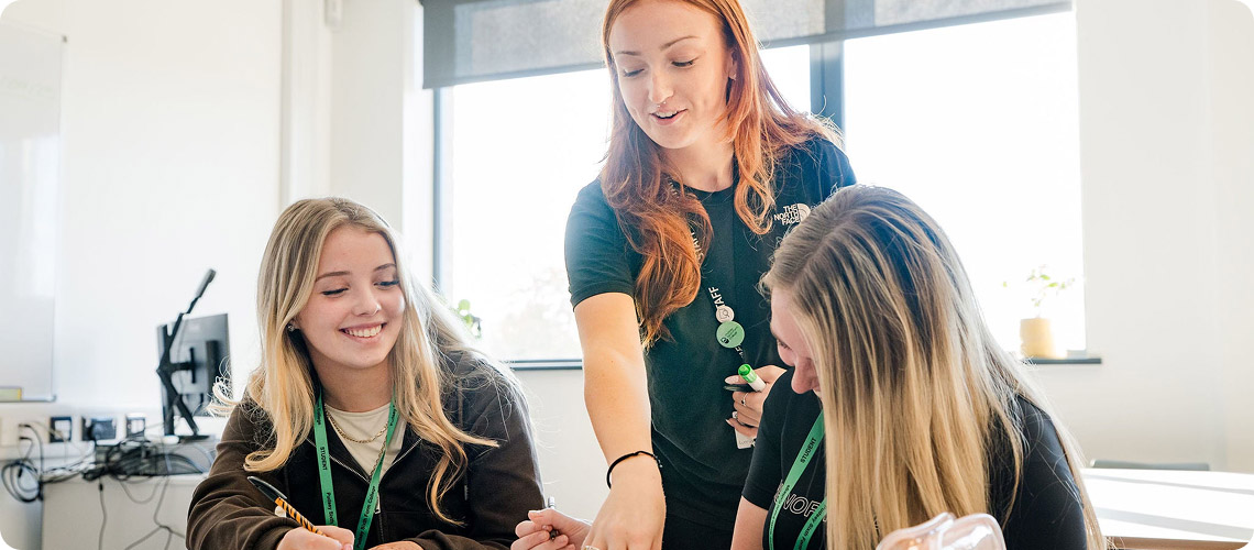 Tutor talking to students in classroom smiling