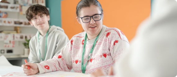 Students sitting down in classroom having discussion smiling