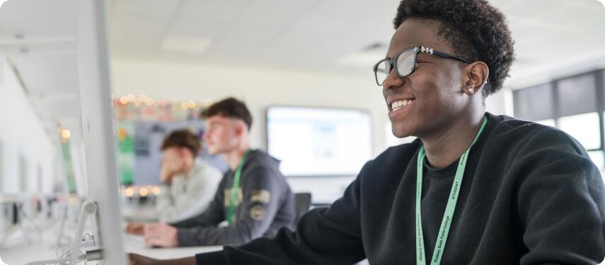 Students sitting down in classroom working on Macs computers