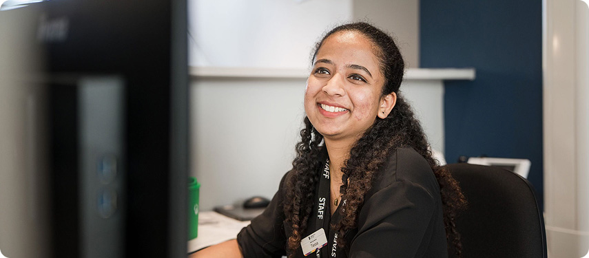 Female receptionist sitting at Pudsey Sixth Form College reception and smiling