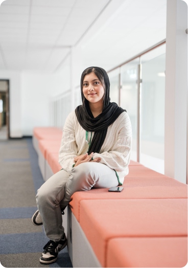 Student wearing headscarf sitting down smiling