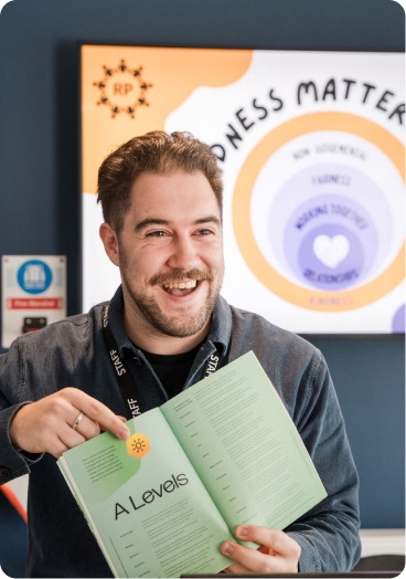 Member of staff holding Pudsey Sixth Form College prospectus smiling 