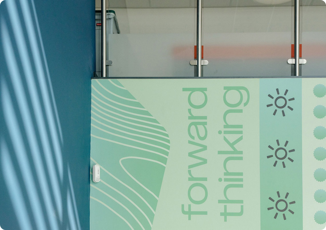 Pudsey Sixth Form College green wall paper with text forward thinking and icons in canteen