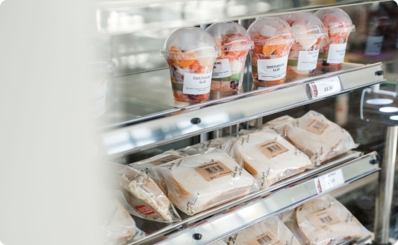 Fresh fruit pots and wrapped sandwiches displayed in fridge shelves