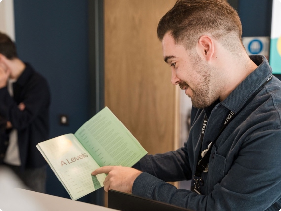 Member of staff pointing the A levels information from the prospectus
