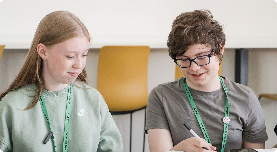 Students wearing green lanyard sitting down having discussion