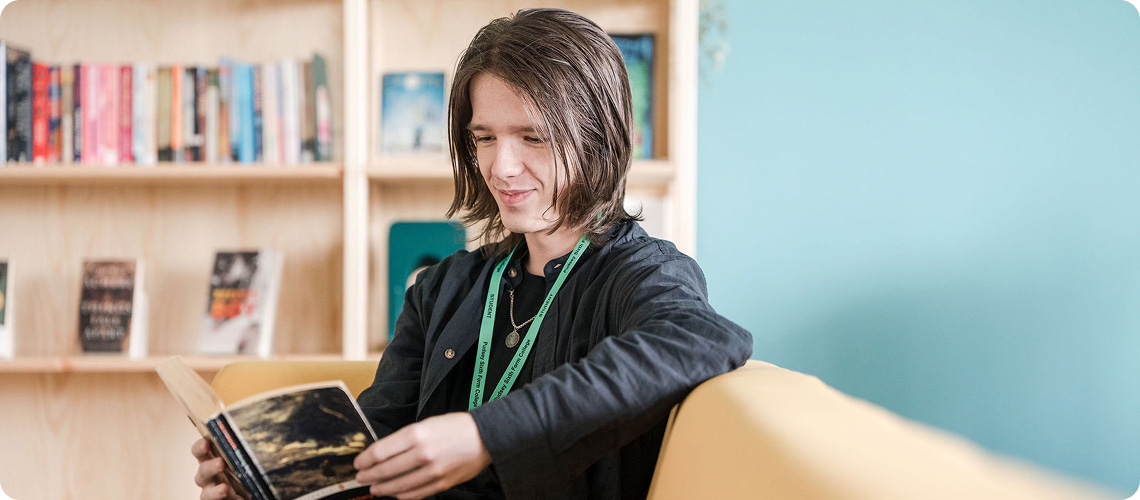 Student sitting down reading a book in library