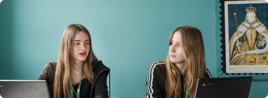 Students sitting in classroom having conversation with picture at the background