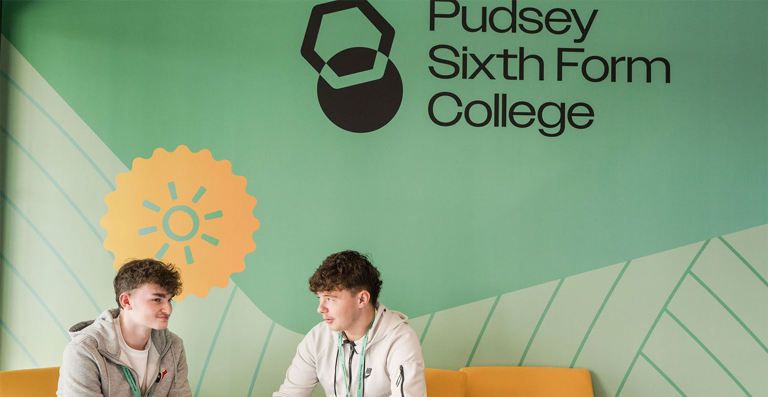 Two students sitting on yellow chair in waiting area talking